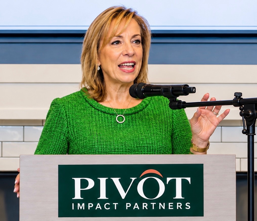 Cynthia Delfino Birdsall speaking at a podium in a green dress